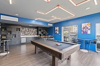 A pool table is in the middle of a room with a blue wall.